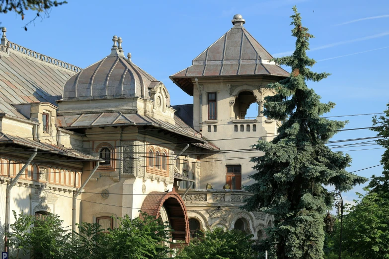 large brown building with four towers that are above trees