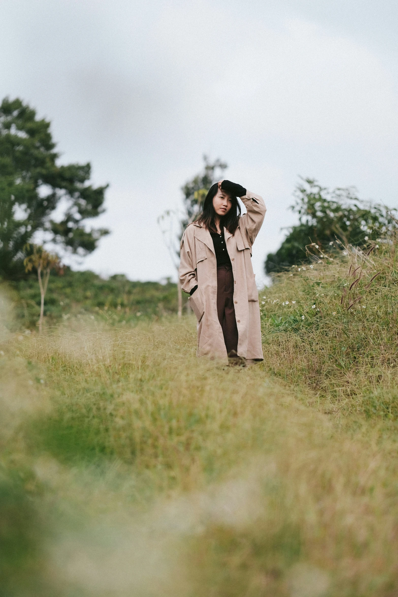 a woman wearing a hat standing in some tall grass