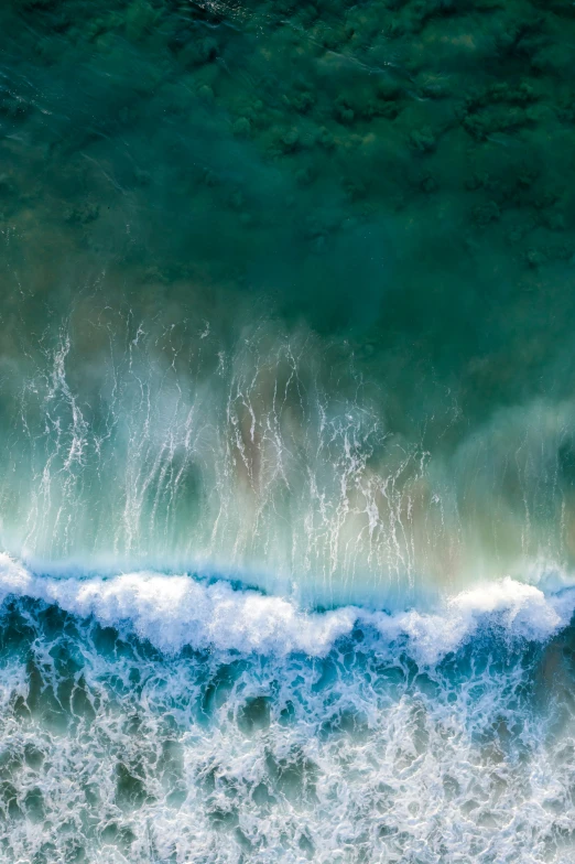 a green sea wave breaking on a sandy shore