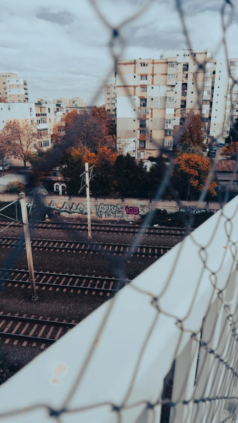 the view of a train yard through a wire fence