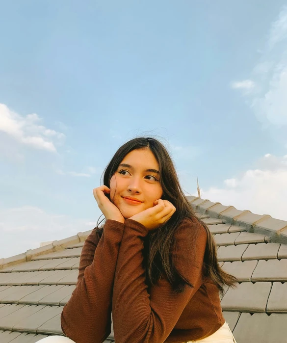 the woman is posing for the camera with her hand resting her chin on her cheek