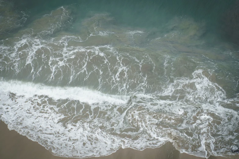 a brown beach that has white water waves on it