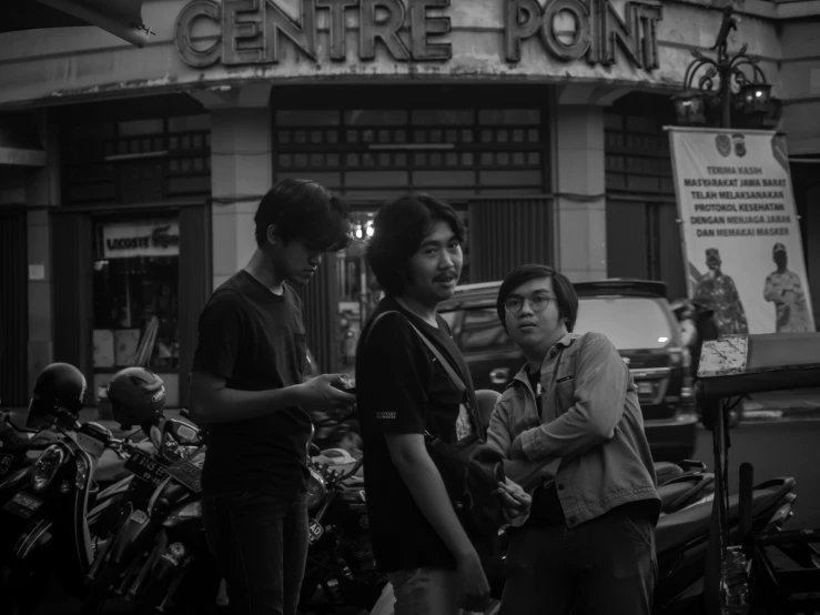 three people standing outside a store near motorcycles