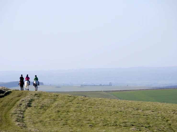 a group of people riding horses down a hill