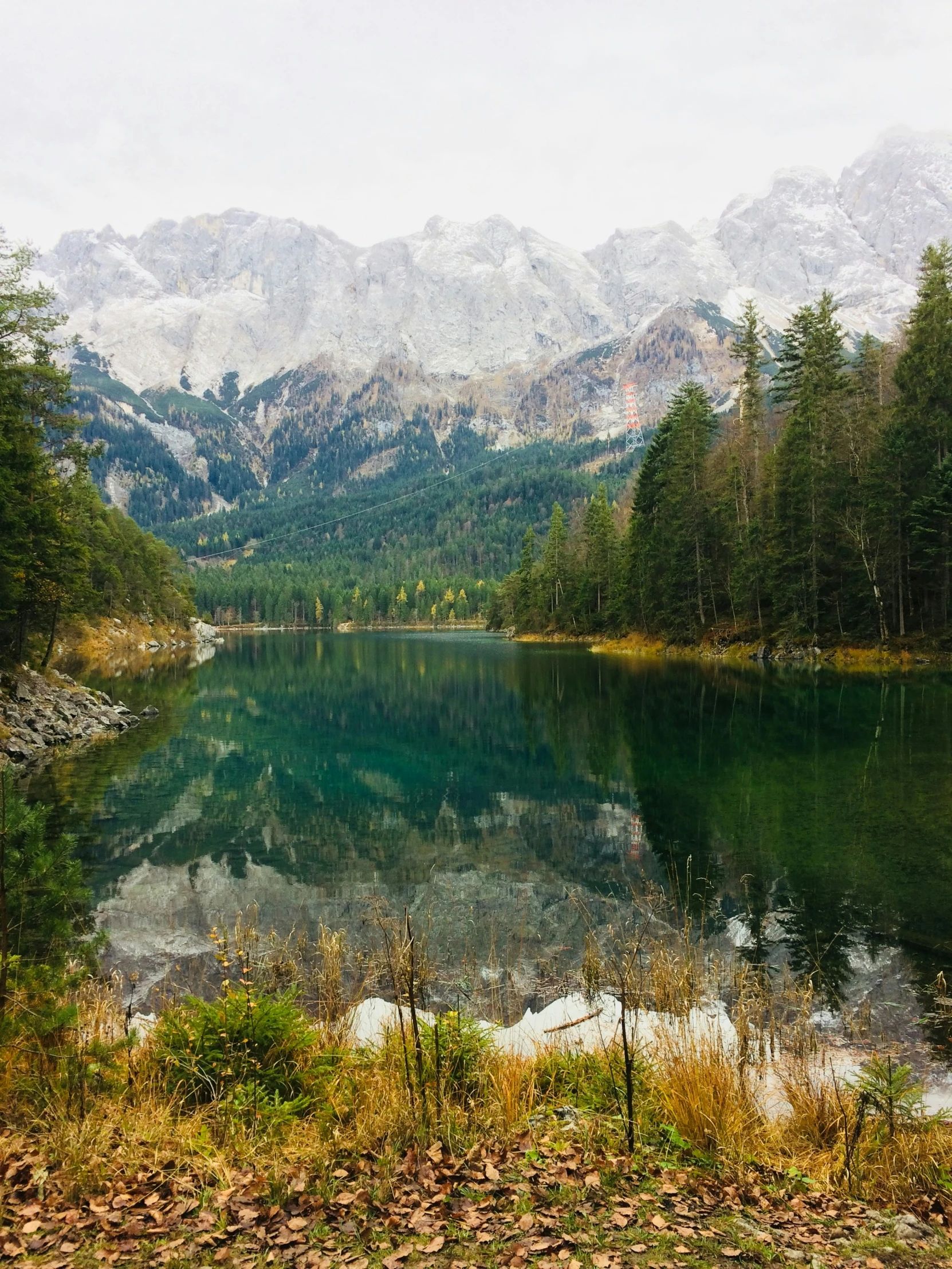 a lake surrounded by mountains and forest in the foreground