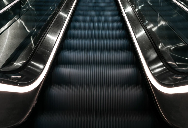 an escalator in a subway station, showing one hand