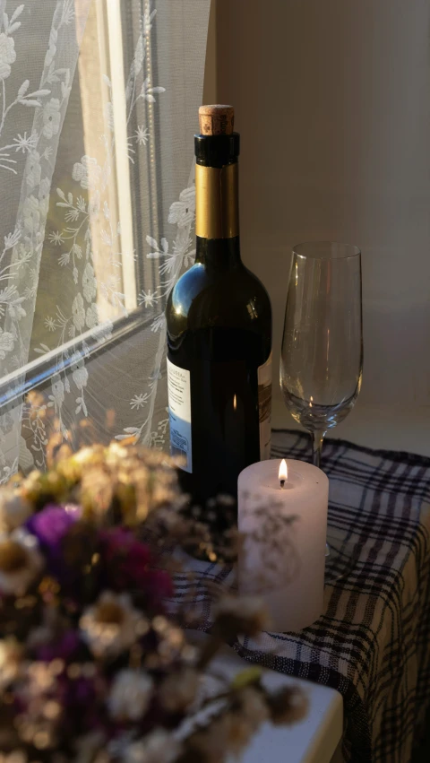 a bottle and glass next to a table with flowers