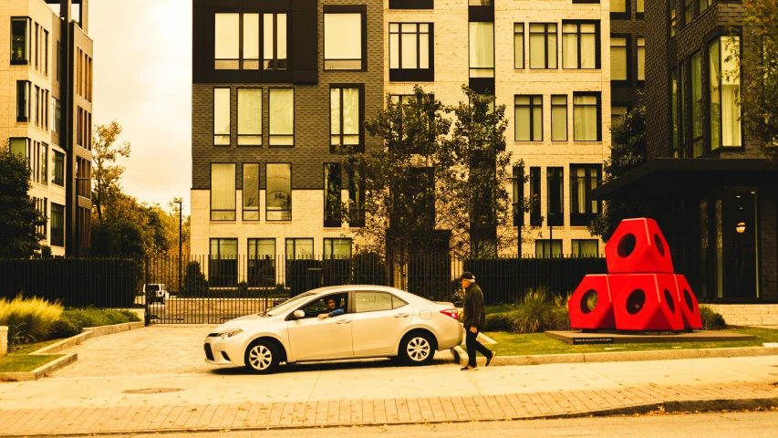 a white car driving down a street next to tall buildings