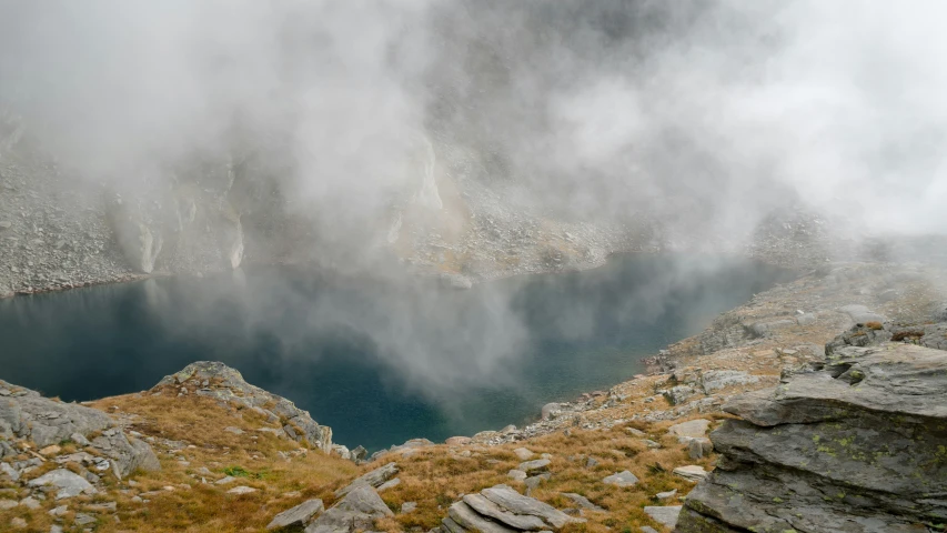 a mountain lake surrounded by rocks and fog