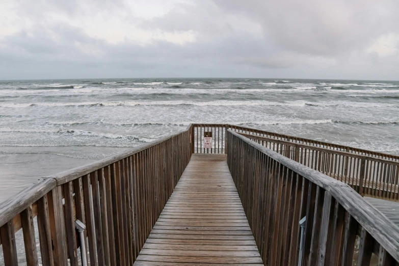 the boardwalk leads down to the ocean from a pier