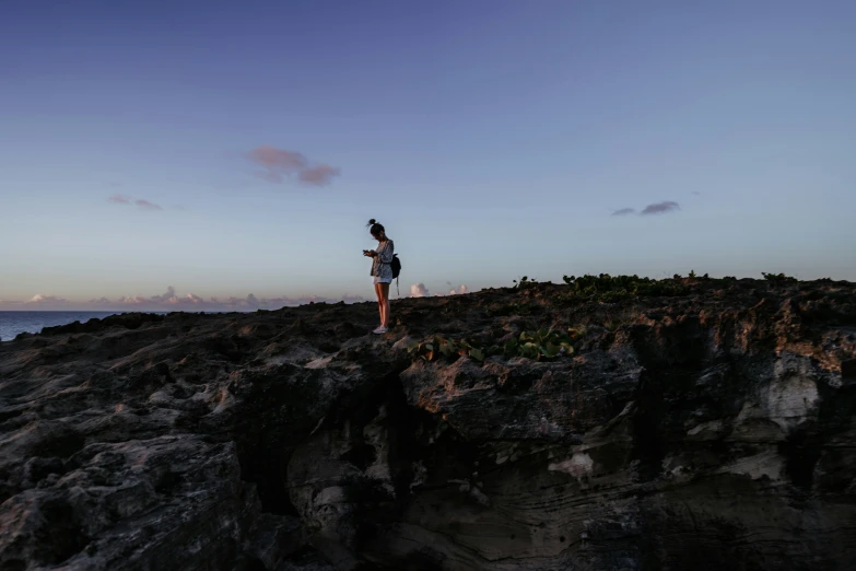 a person is standing at the top of the mountain looking down at the water and the rocks