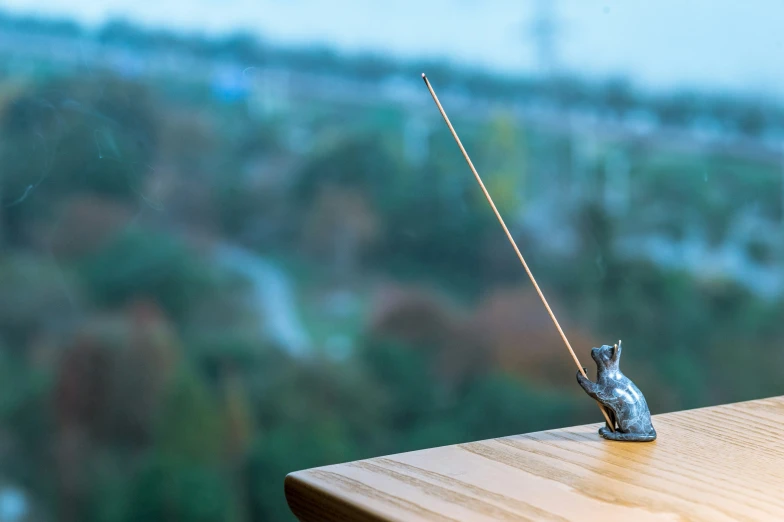 a small metal mouse hooked up to a string on a wooden table