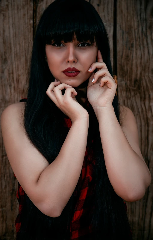 a woman with long black hair leaning on the wall