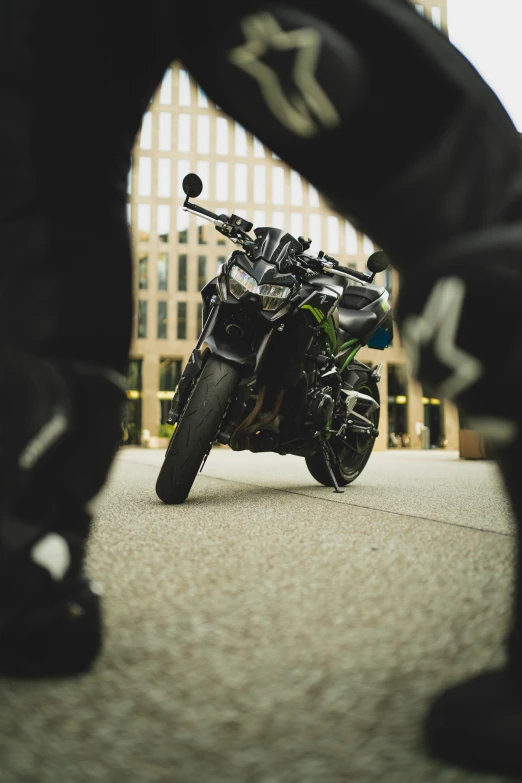 someone stands near a black motorcycle in the city