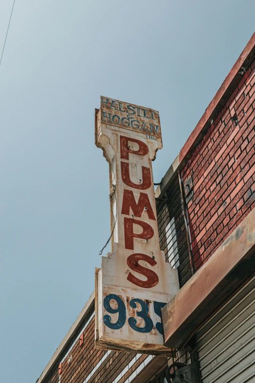 an old sign hangs off the side of a building