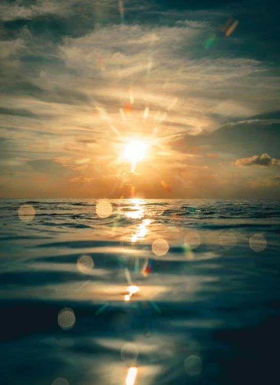 a bright sun setting behind the water