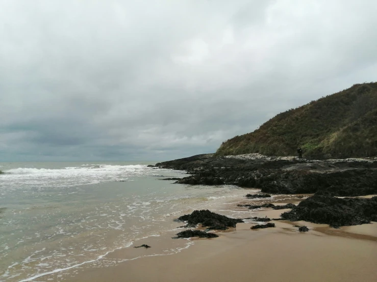 waves crashing on the beach near some rocky coast