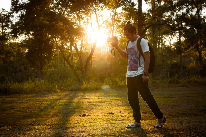 the boy with the back pack is waiting for the sunset