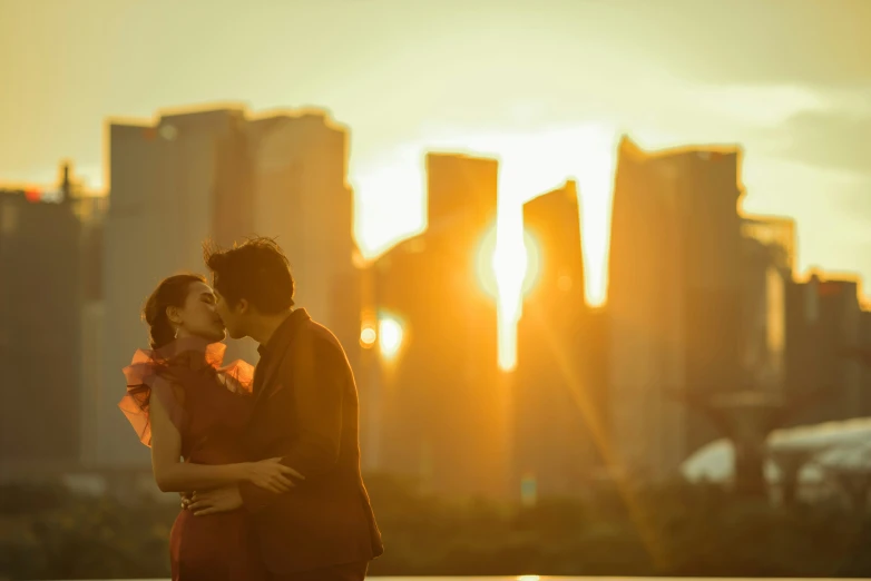 the couple is kissing and standing in front of a city skyline