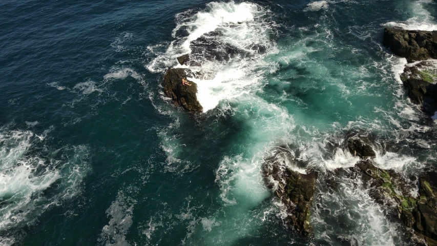 there is some small waves crashing around the rocks