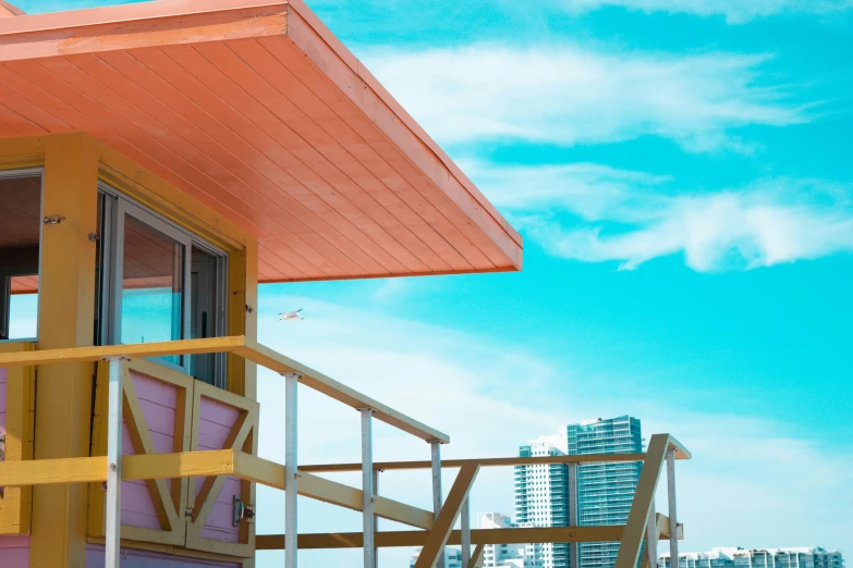 a colorful house on the beach with the ocean and high rise buildings