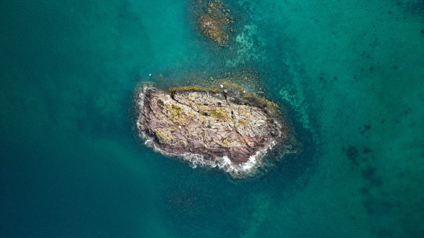 an aerial s of the ocean with rocks