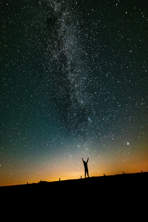 two people standing on top of a hill under a sky full of stars