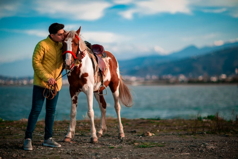 a man standing next to a brown and white horse