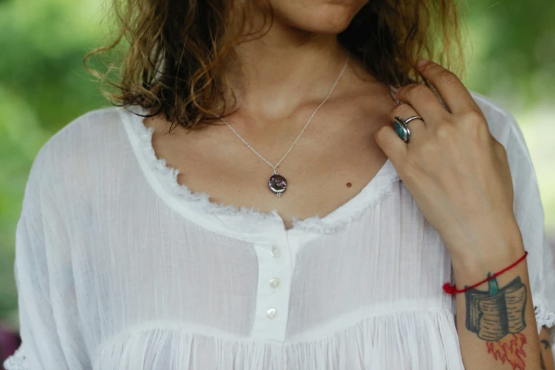 a woman with large tattoos and a white top is wearing a red celet