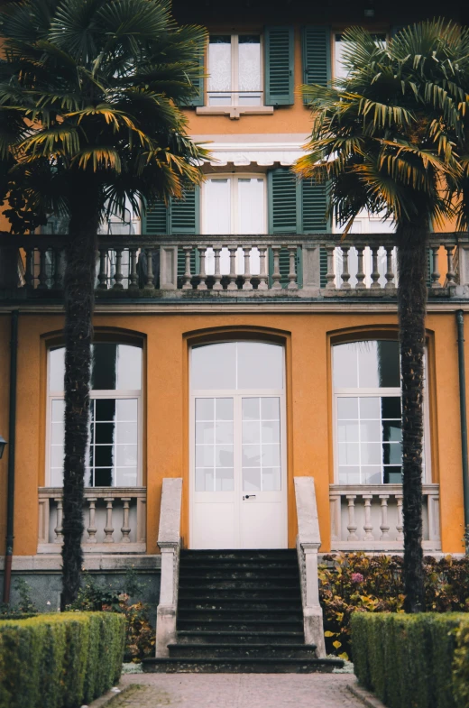 an orange building is shown with two tall palm trees