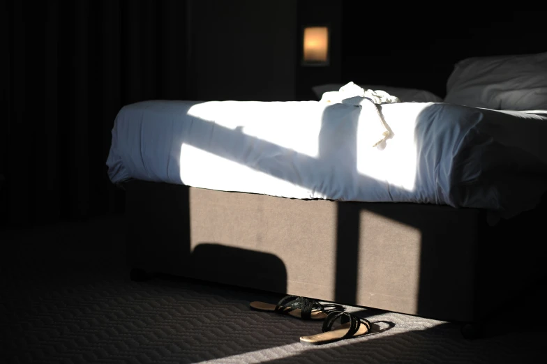 the shadows cast onto the bed with shoes beside it