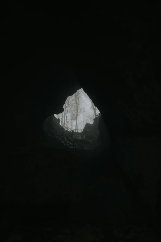 a black cave with a snow covered mountain in the background