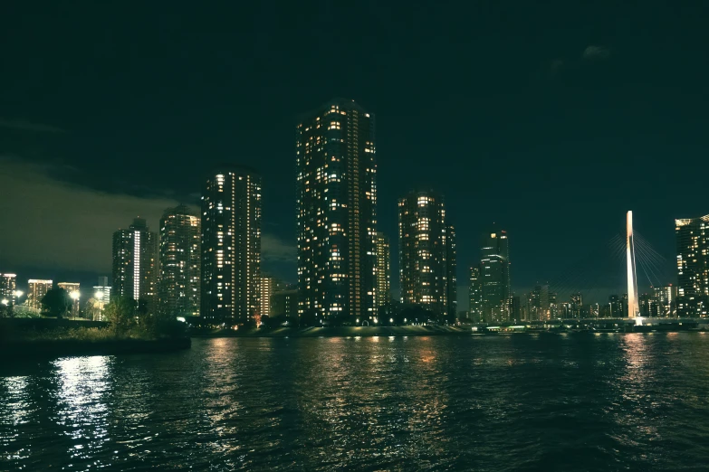 the water has some lights reflecting off of the building in the city