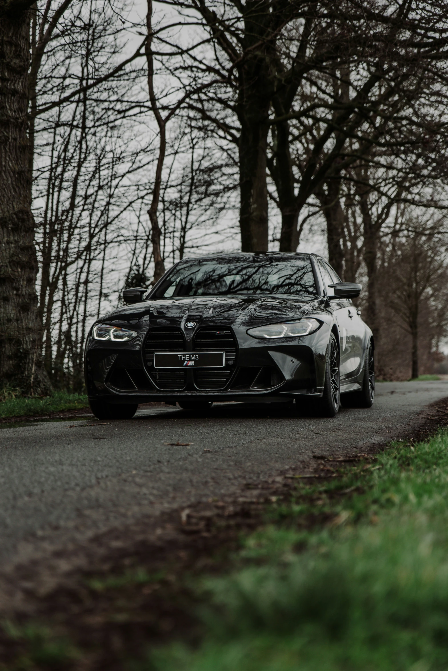 the front end of a black sports car on a road