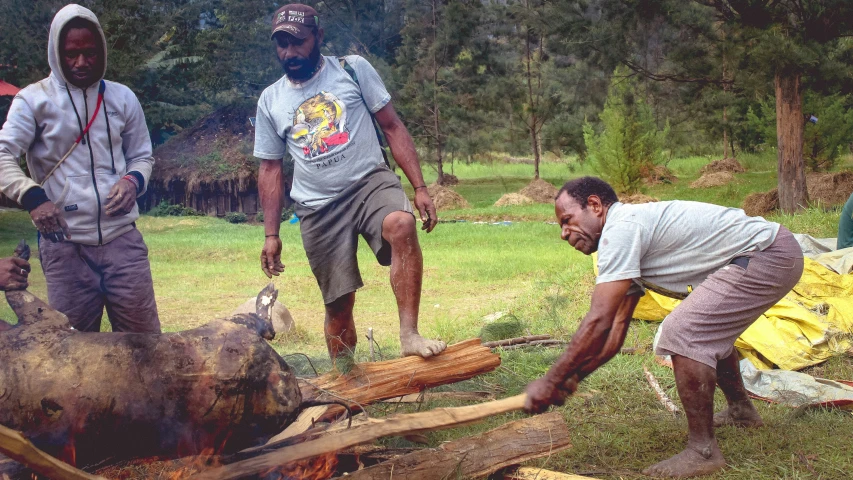 three people are standing around and looking at a small boar