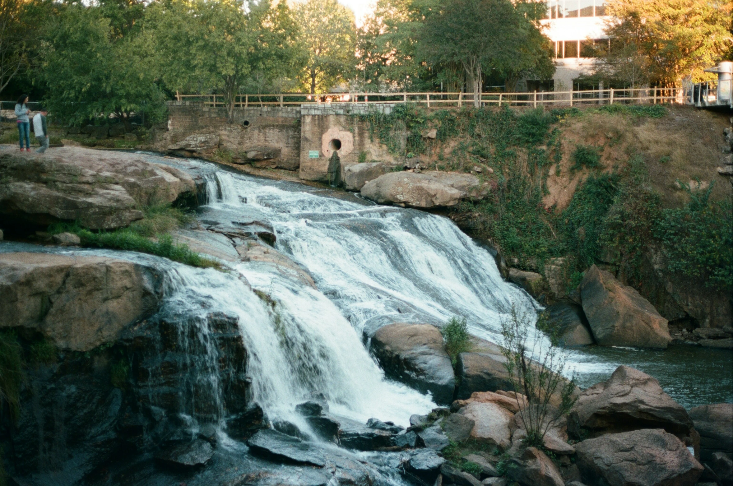 a man stands on a bridge above a waterfall