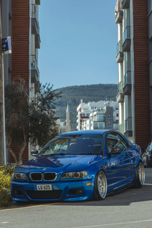 a blue car parked in the road near buildings