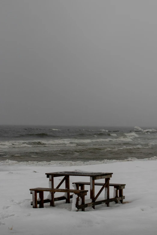 an empty bench on the beach during the winter