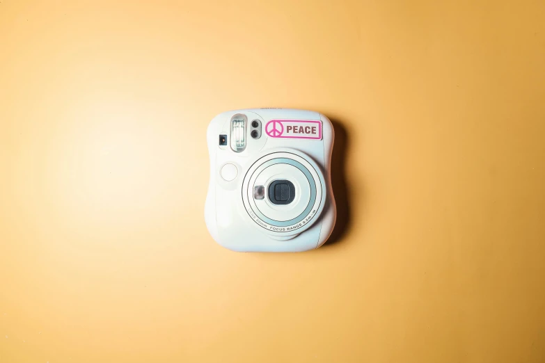 a white po camera sitting on a yellow wall