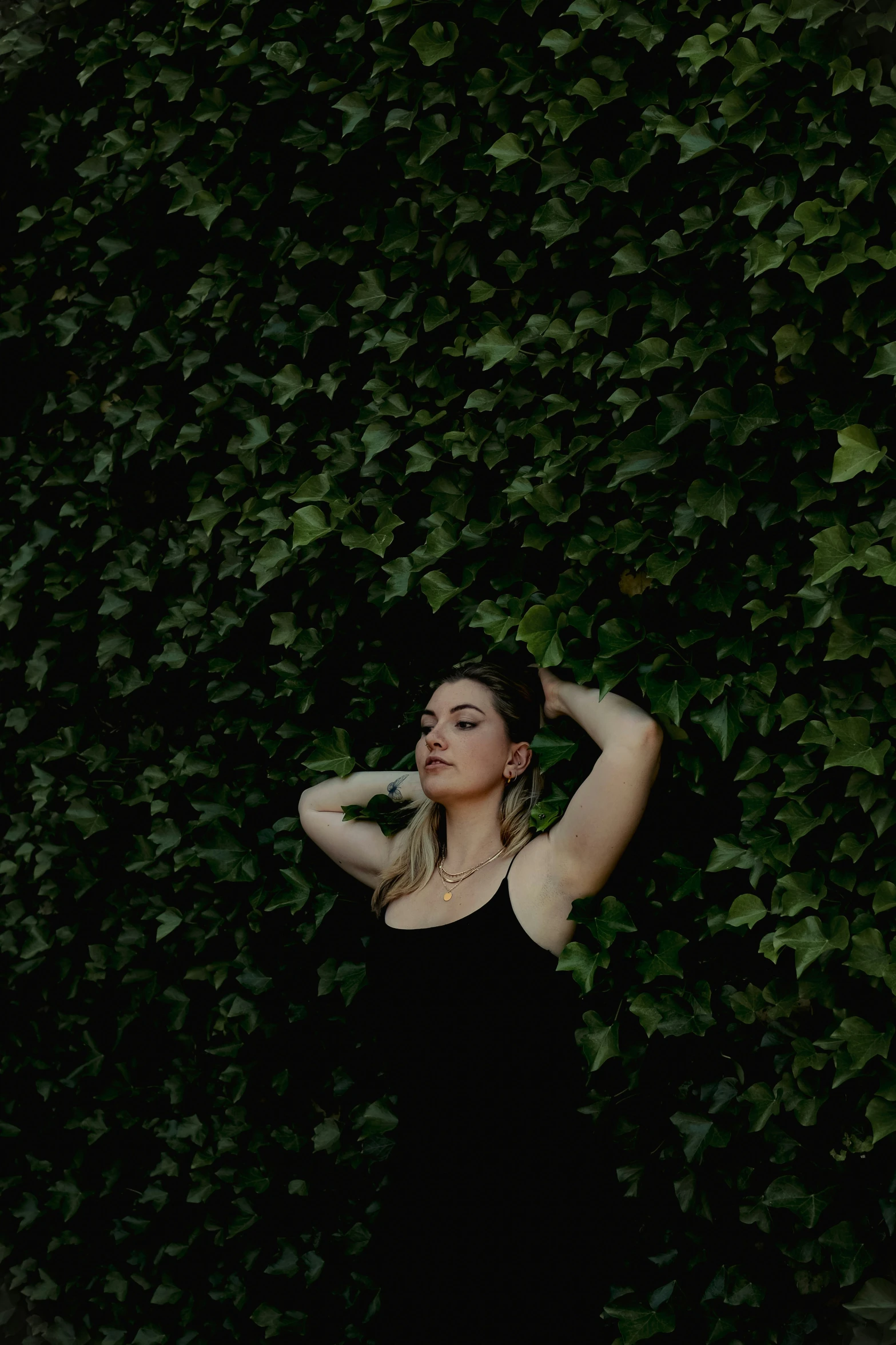 a woman standing against a wall in a black dress