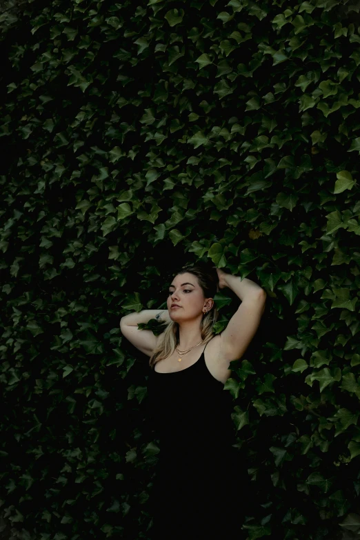 a woman standing against a wall in a black dress