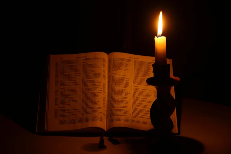 a candle is lit up in front of an open bible