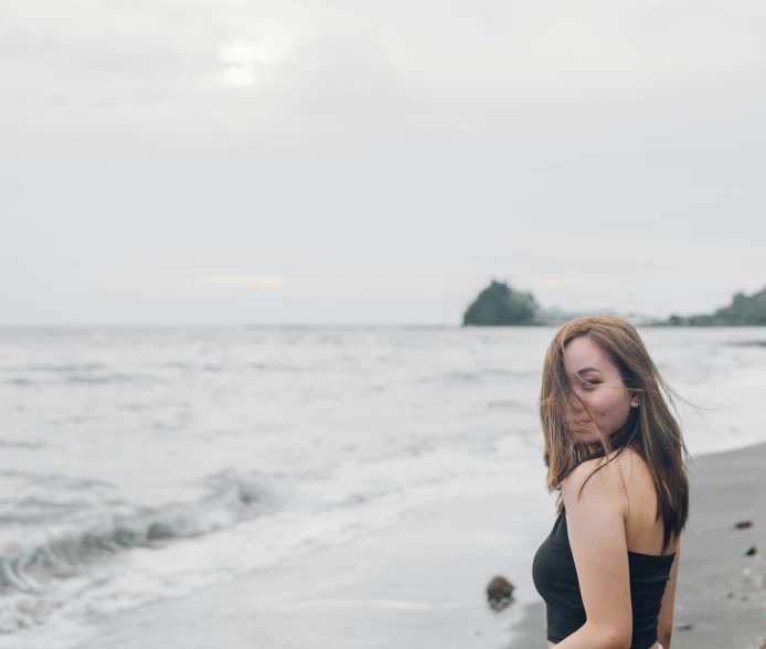 a girl on the beach looks out into the distance