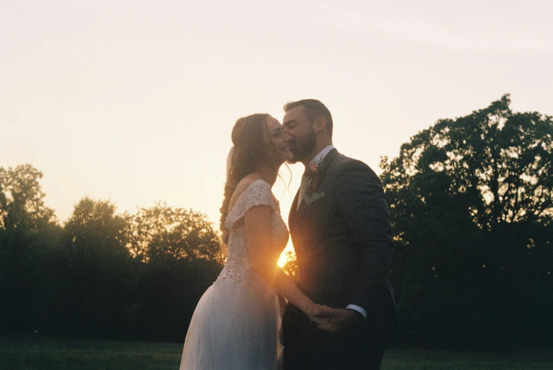 two people kissing in the grass and trees