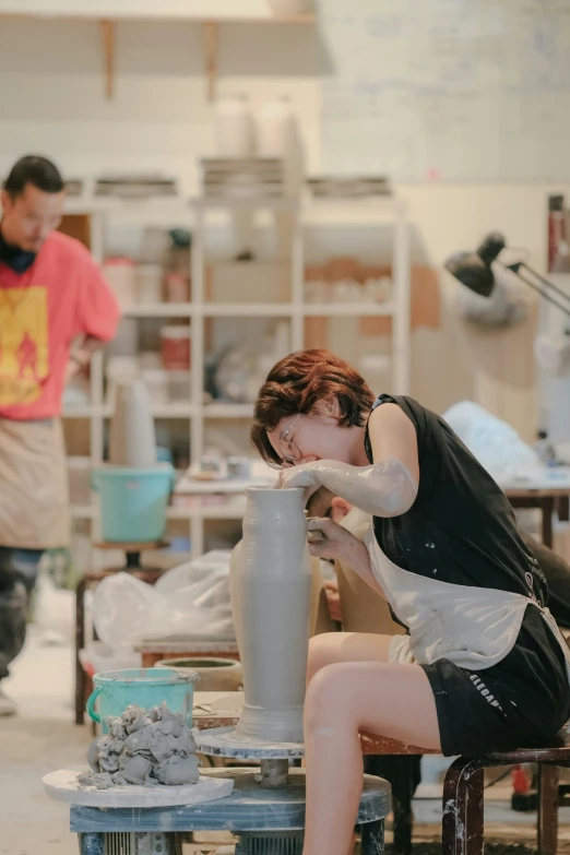 a woman working on a large vase inside a shop