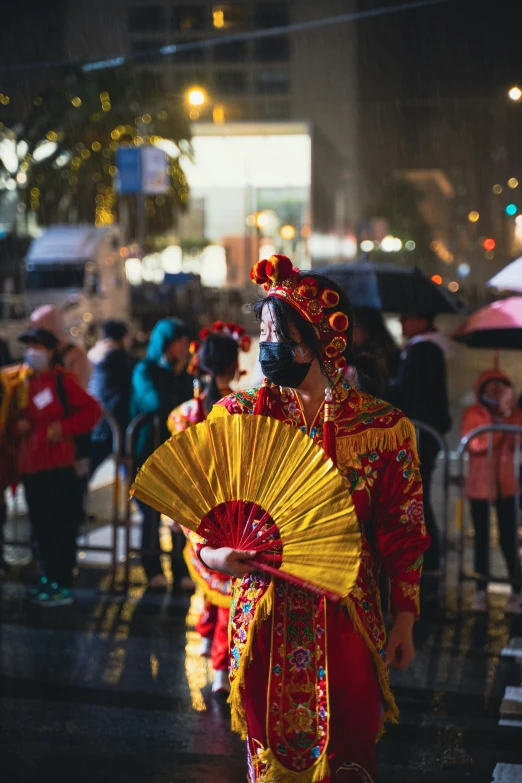 an asian man in costume holds a yellow and red fan