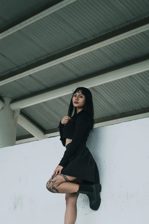 a woman is leaning on a wall with her leg in the air