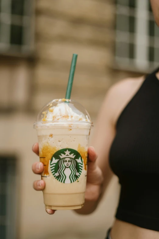 a woman holding a starbucks drink in one hand and looking at the camera