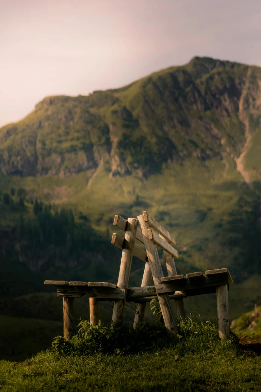 a wooden bench in the mountains near a hillside