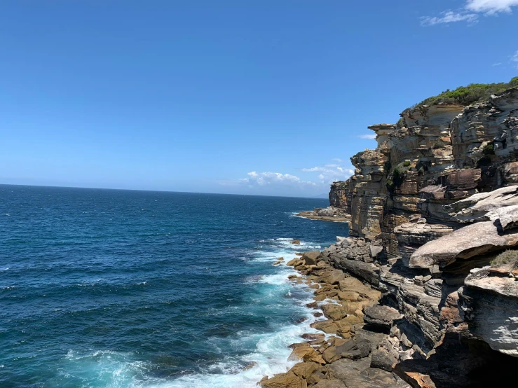 the water is rushing off of the cliff by the beach